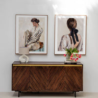Wooden console table with decorative items against a white wall with framed portraits, limited edition prints.