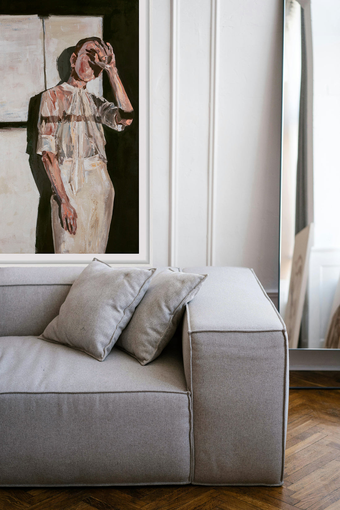 Gray sofa with decorative pillows in a room with a framed art print on the wall.