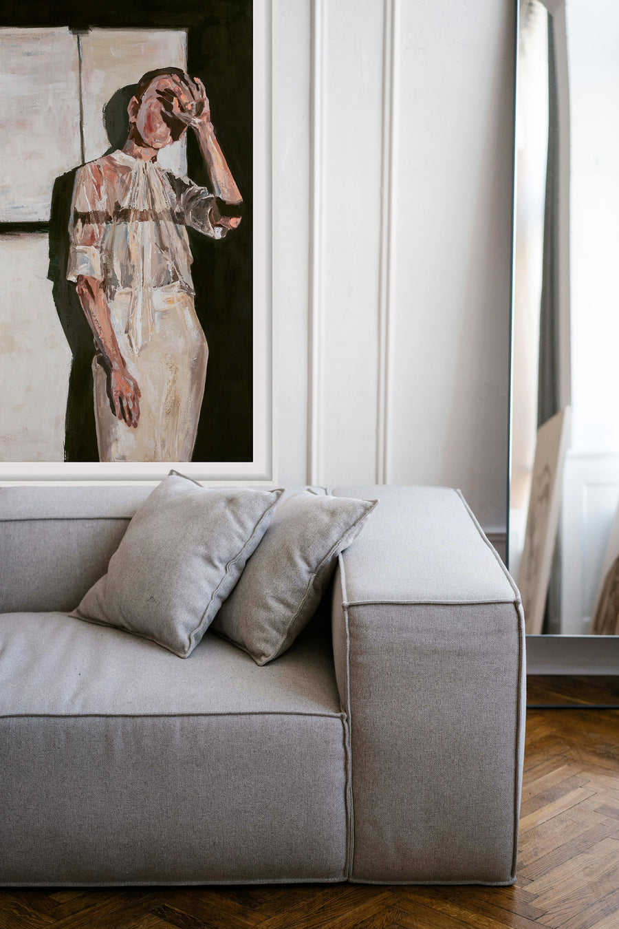 Gray sofa with decorative pillows in a room with a framed art print on the wall.