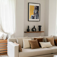 Living room with beige sofa, decorative pillows, a shelf with vases and a fine art print