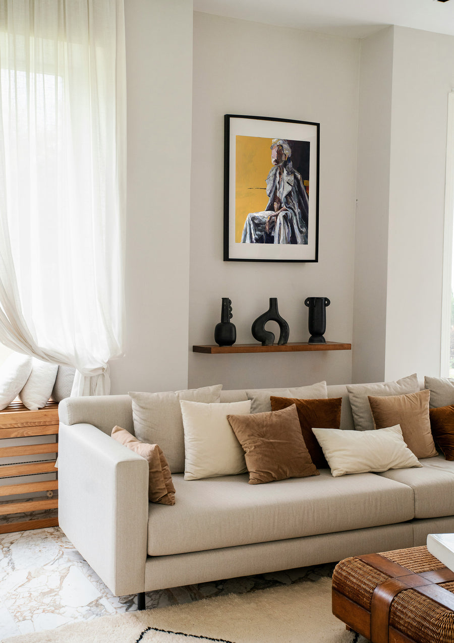 Living room with beige sofa, decorative pillows, a shelf with vases and a fine art print